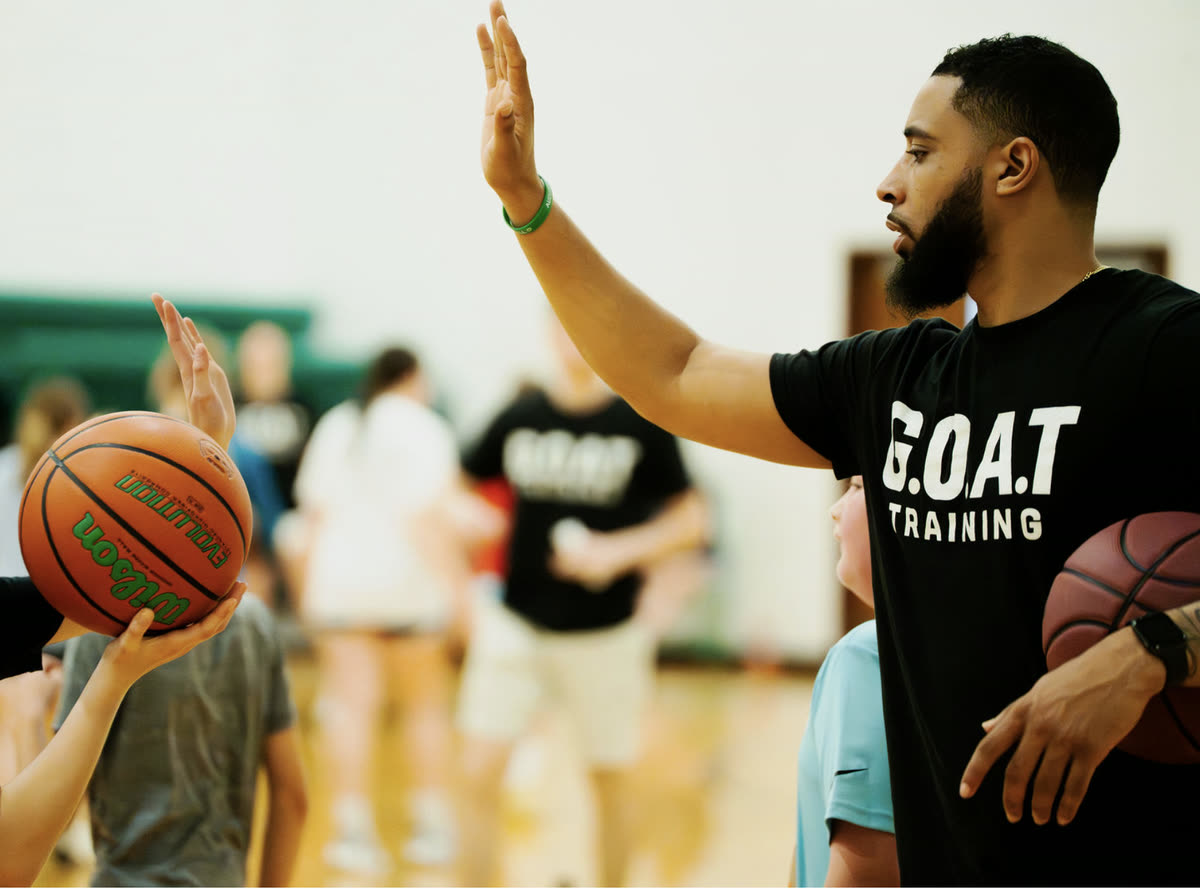 Coach Keith Williams high-fiving a young athlete at a G.O.A.T Training session